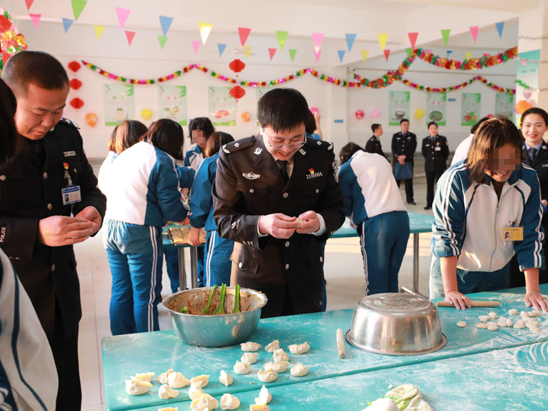 （用）省司法廳戒毒管理局局長段劍平（中）同干警、戒毒學(xué)員一起包餃子。