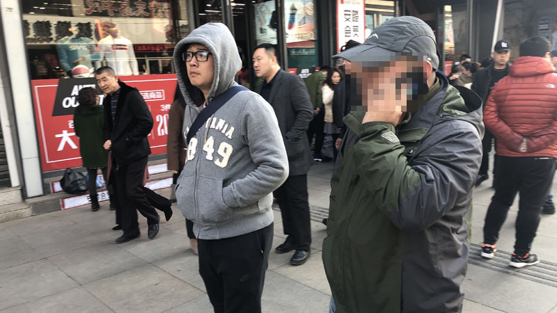 記者和王剛一起在步行街上尋找可疑人員（擋臉）