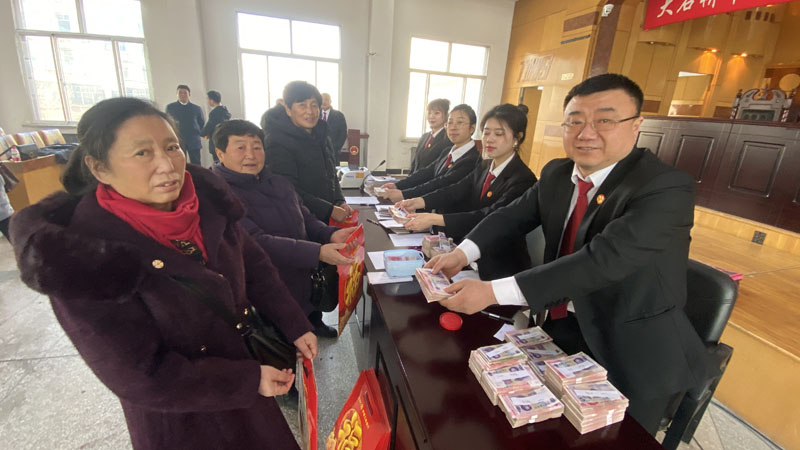 徐斌（左二）領(lǐng)取工資款；右一是大石橋市人民法院執(zhí)行員王敬偉